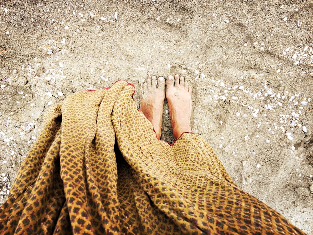 person in brown pants standing on gray sand