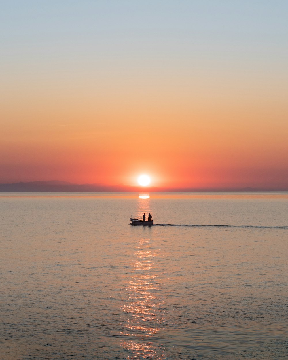 silhouette of 2 people riding on boat on sea during sunset