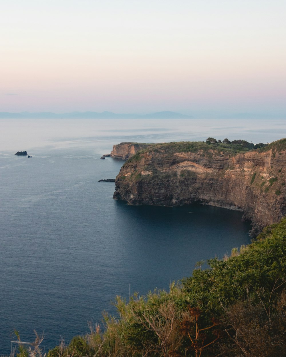 brown and green mountain beside blue sea under blue sky during daytime