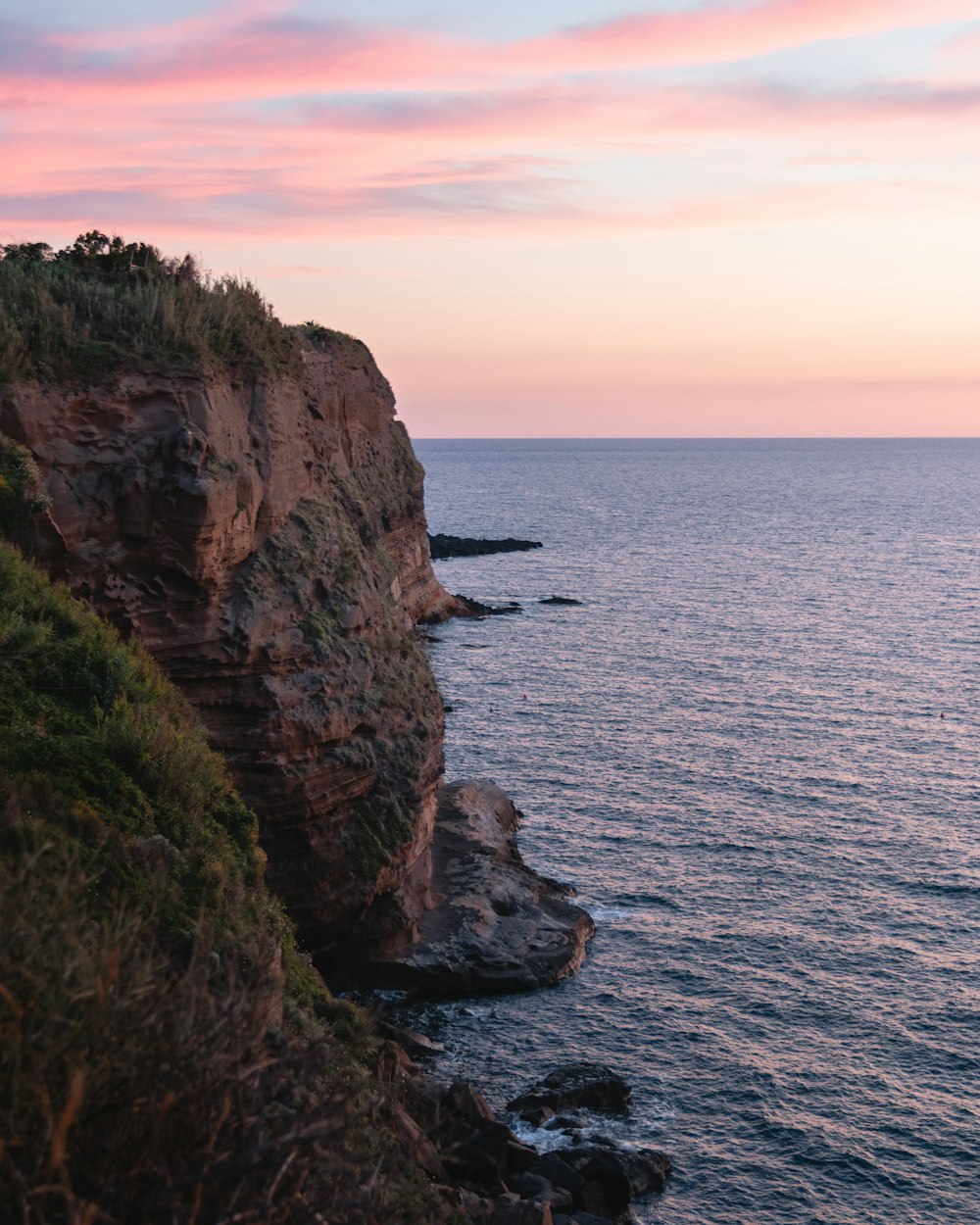 brown rocky mountain beside sea during sunset