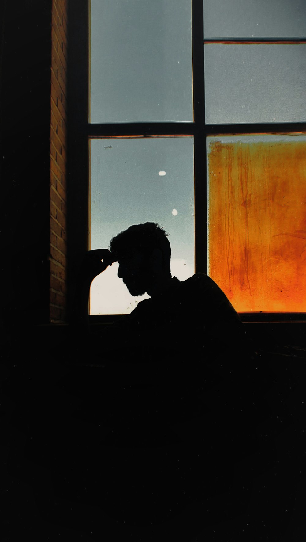 man in black shirt sitting near window