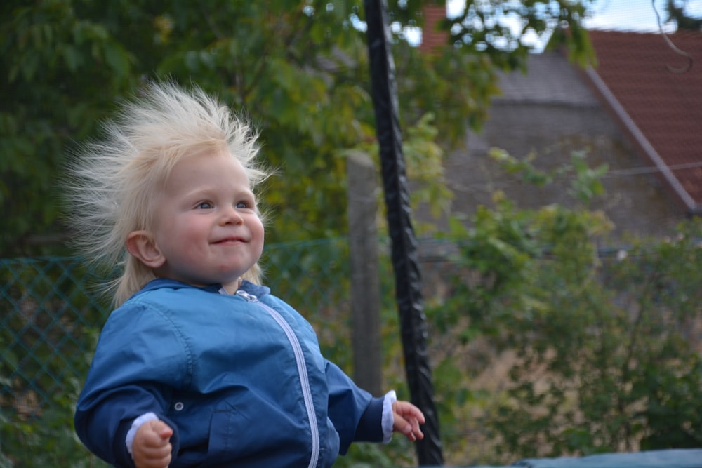 child in blue jacket on swing during daytime