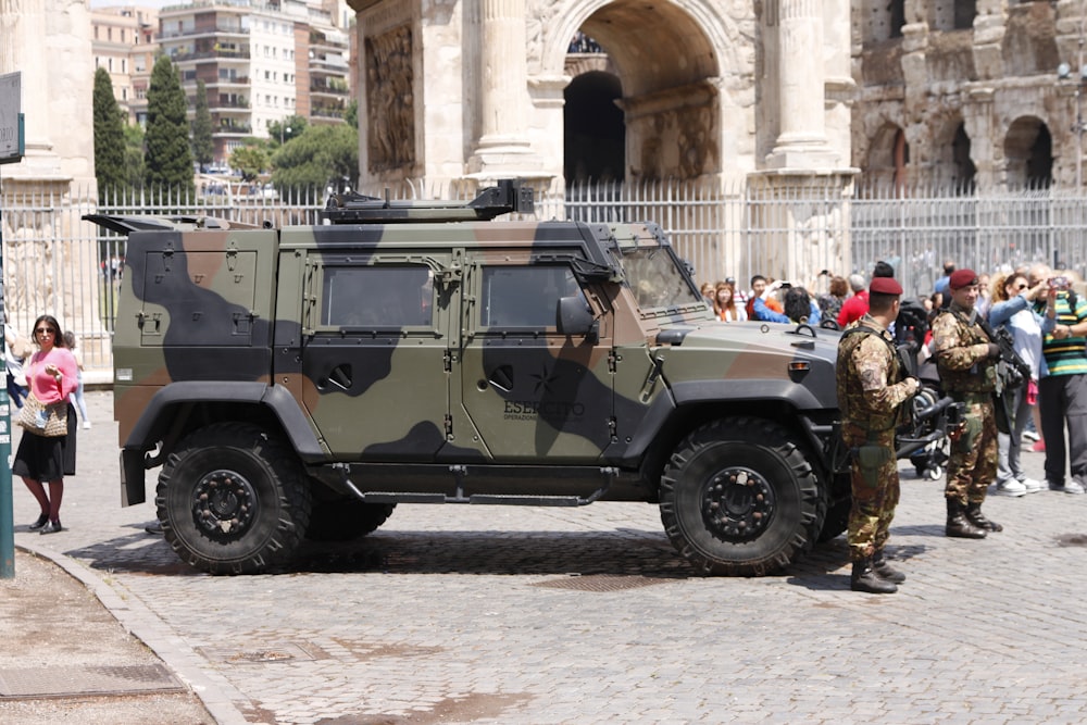 people riding on green and brown camouflage military vehicle during daytime