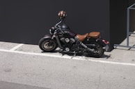 A motorcycle parked beside a dark blue wall, capturing its sleek silhouette.