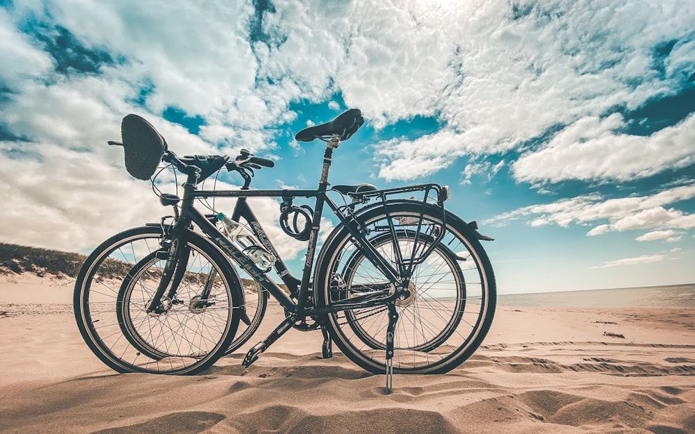 낮 동안 푸른 하늘 아래 갈색 모래 위에 검은 통근 자전거