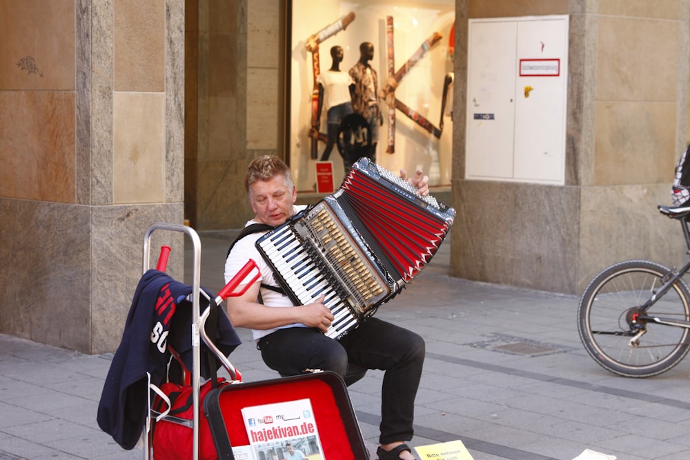 man in black jacket playing red and white piano