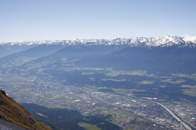 A panoramic view of fertile farmland with distant mountains and a small river.