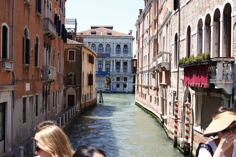 people walking on river between concrete buildings during daytime