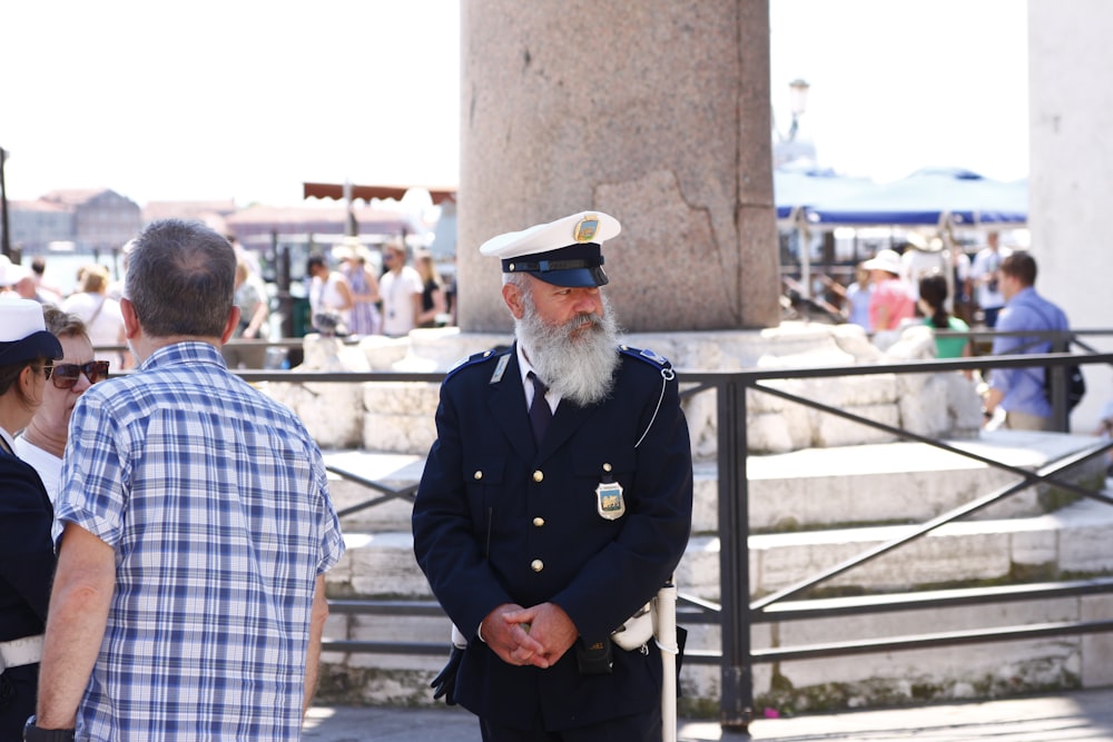 man in black police uniform standing beside brown concrete wall during daytime