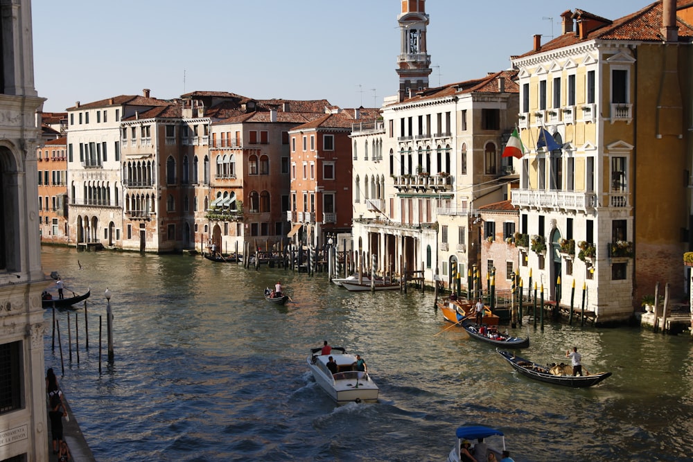 people riding on boat on river between concrete buildings during daytime