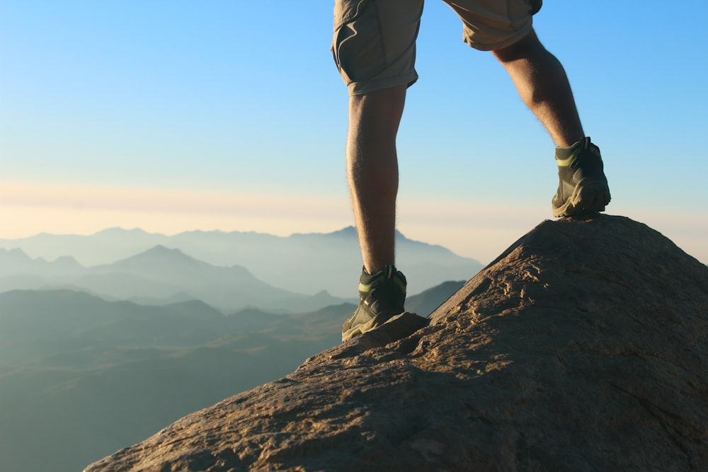 man in green shorts standing on rock formation during daytime