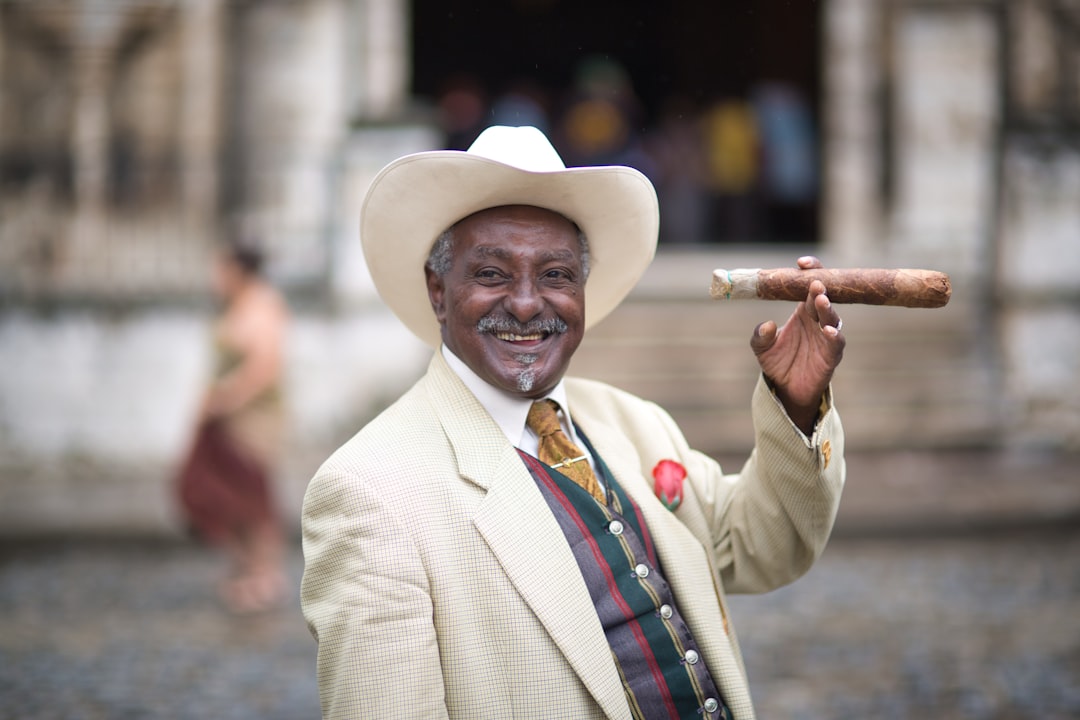 man in white cowboy hat and gray blazer holding brown wooden stick