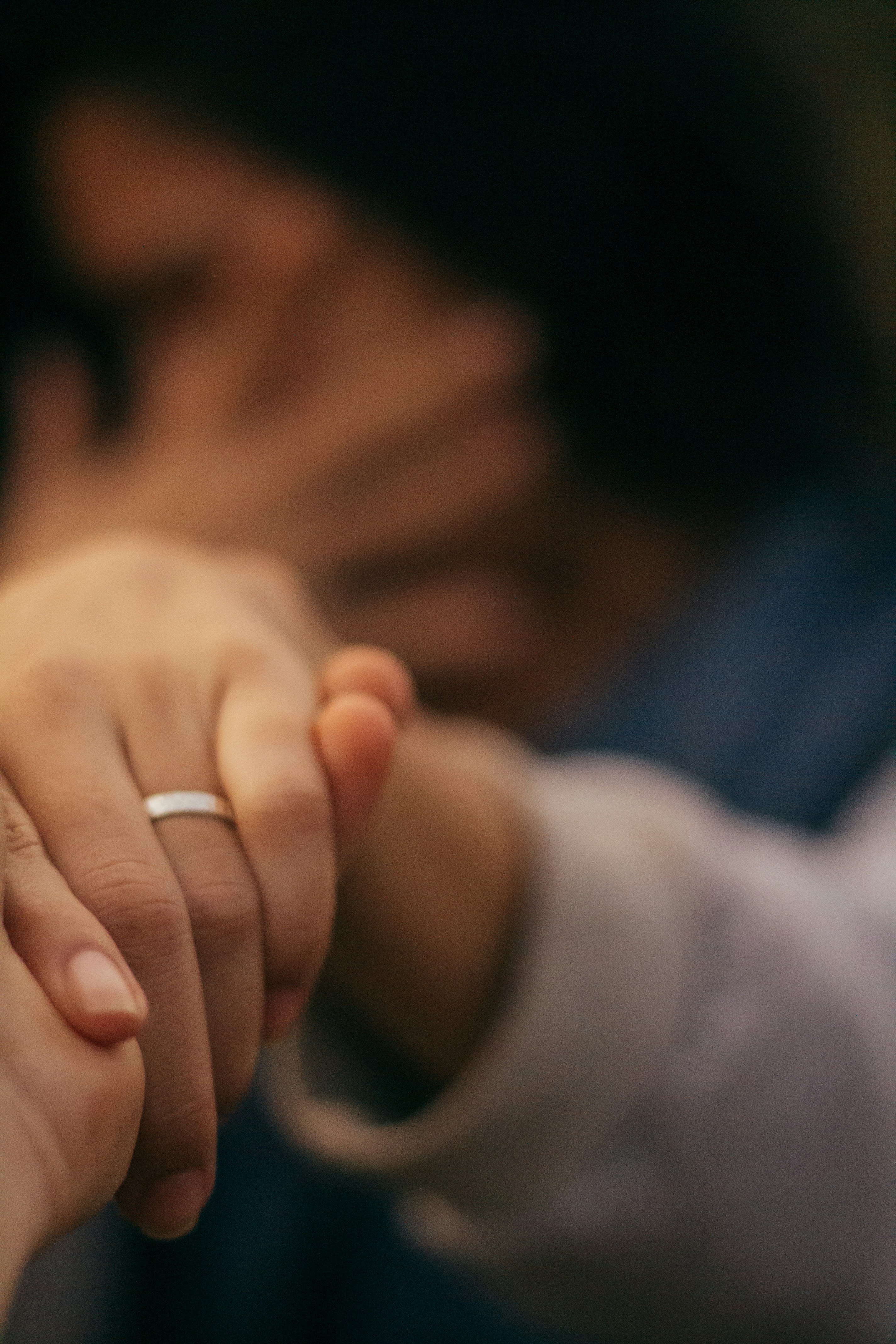 person wearing silver ring holding babys hand