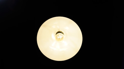 A centered, illuminated round light fixture casting a soft glow against a dark background.