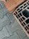 Concrete pavers are laid in a herringbone pattern beside a large, hollow, red clay brick. The textures of both materials are prominent, showing detailed grooves and rough surfaces.