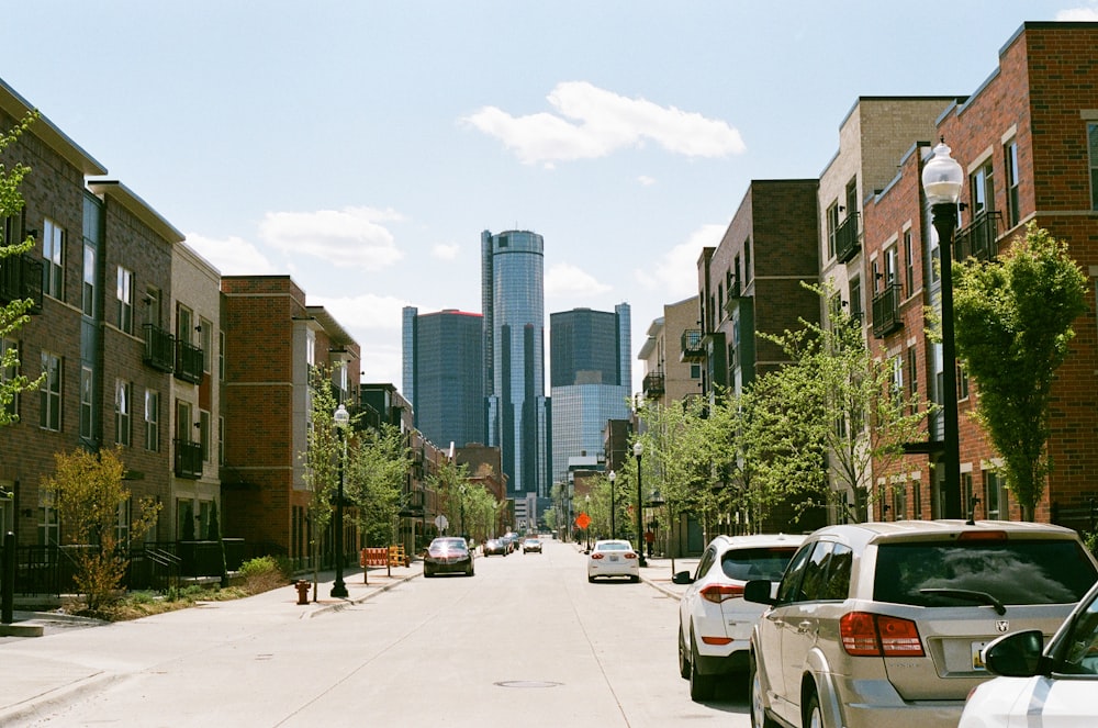 cars parked on side of the road near high rise buildings during daytime