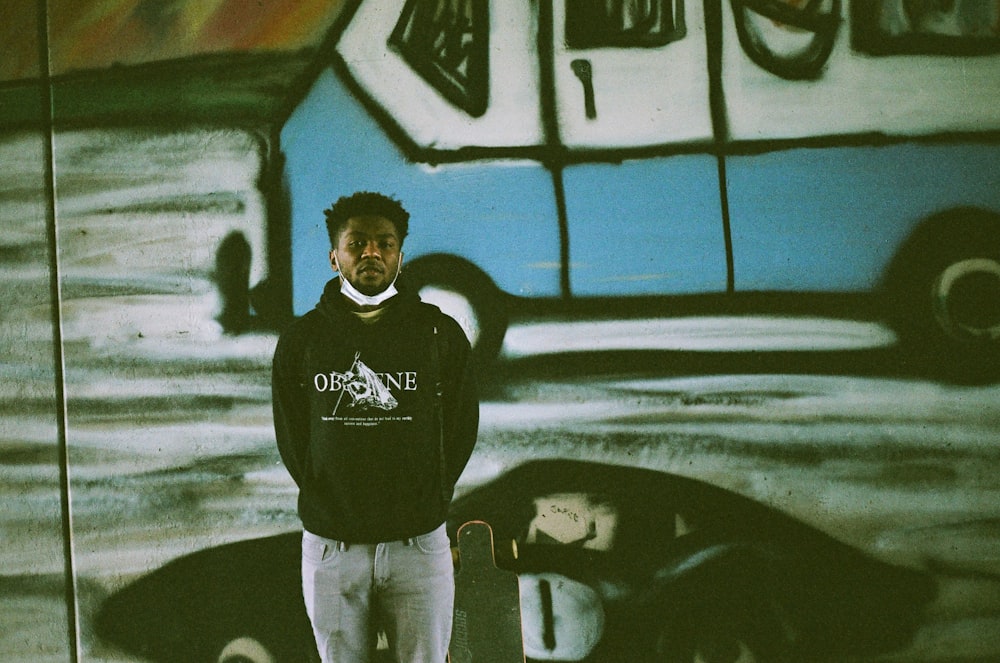 man in black hoodie standing beside wall