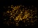 Glowing coals with a dark background create a warm, fiery effect. Randomly scattered, pieces of coal emit a bright orange-yellow hue, providing a contrast against the surrounding darkness.