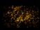 Glowing coals with a dark background create a warm, fiery effect. Randomly scattered, pieces of coal emit a bright orange-yellow hue, providing a contrast against the surrounding darkness.
