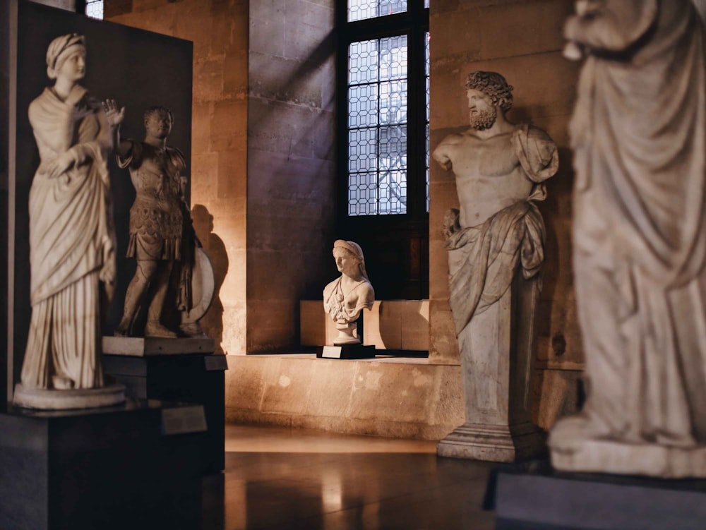 a group of statues in a room with windows