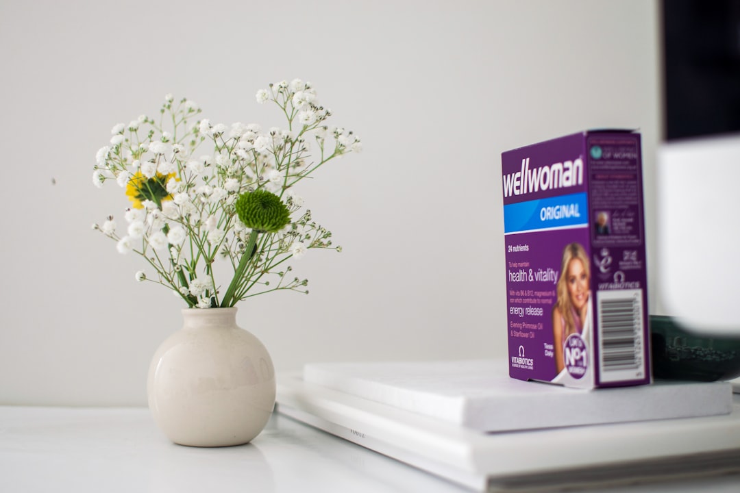 white flowers in white ceramic vase, Flower vase next to woman vitamin supliments
