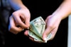 person holding fan of 100 us dollar bill
