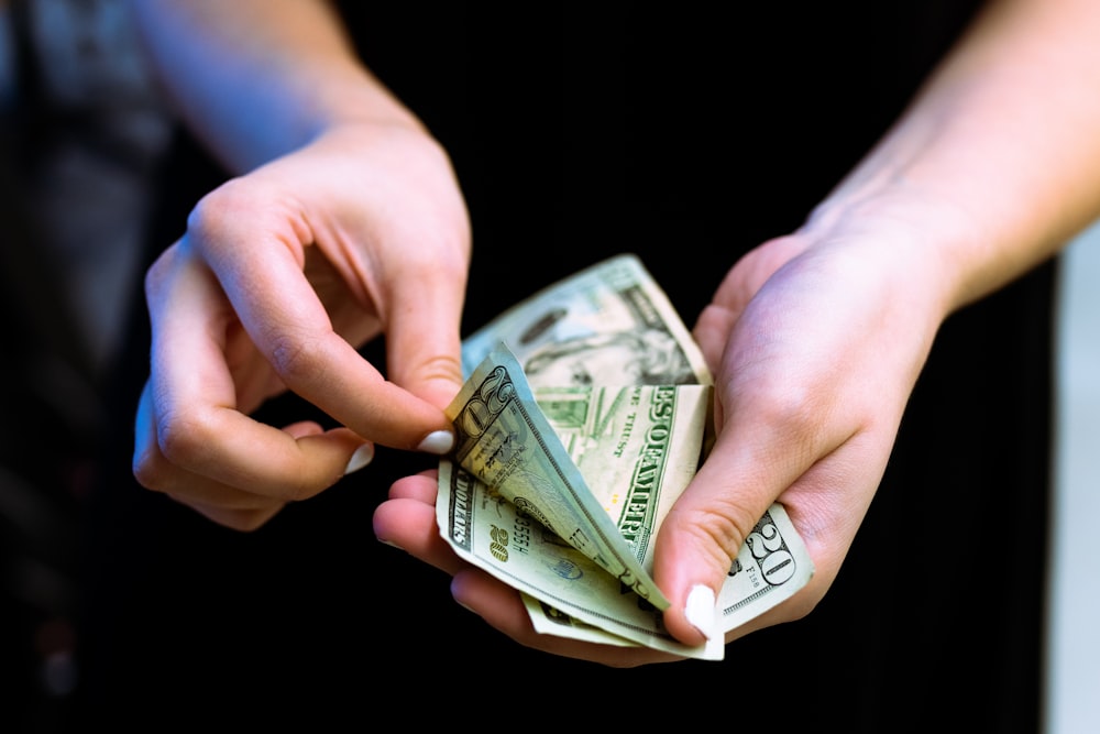 person holding fan of 100 us dollar bill