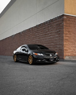black porsche 911 parked beside brown brick wall
