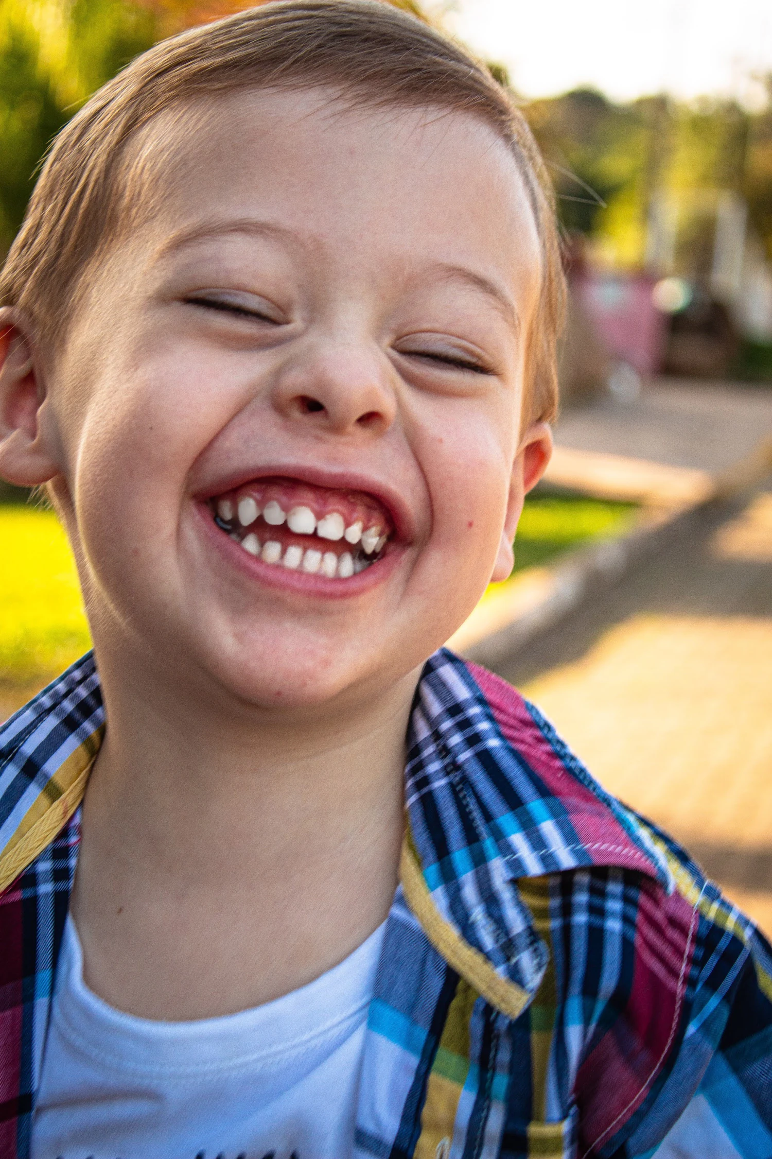 Smiling young boy in a plaid shirt, laughing outside