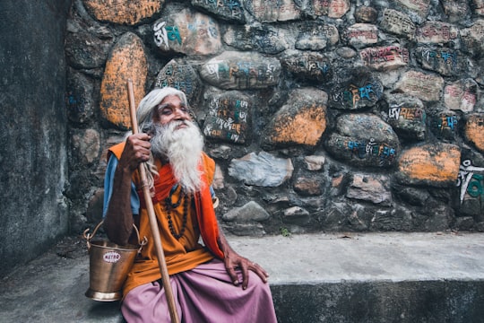 man in red and white robe holding stick in Katmandu Nepal