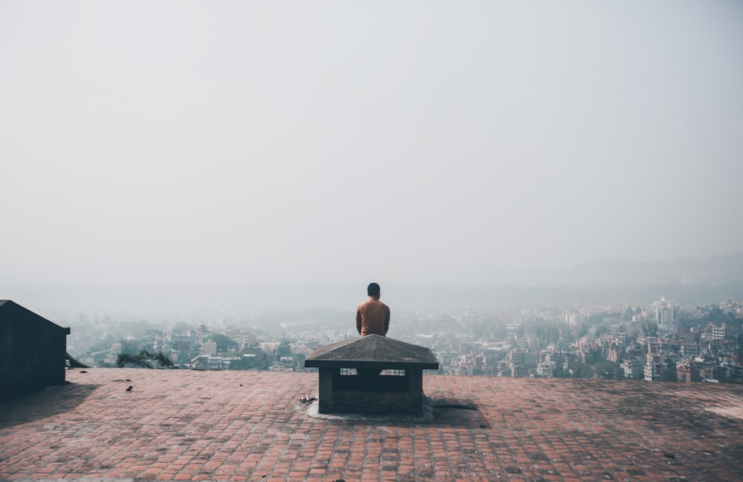 man sitting on black concrete bench during daytime