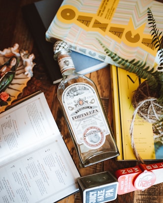 A rustic wooden table displaying bottles ofmezcal and tequila alongside agave plants and traditional Mexican pottery.