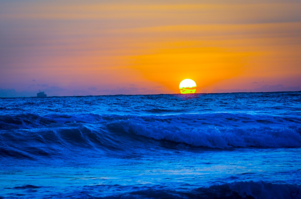 ocean waves crashing on shore during sunset