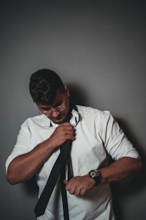 A stylish gentleman adjusting his tie in front of a mirror, showcasing captain & carter accessories