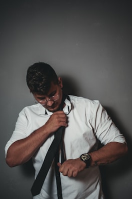 A man adjusting a silk tie in front of a mirror, showcasing attention to detail.