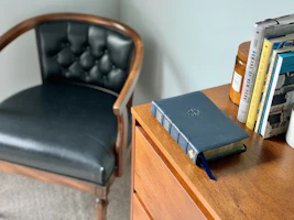A vintage nightstand with aged brass handles, holding a classic alarm clock and a stack of well-loved novels.