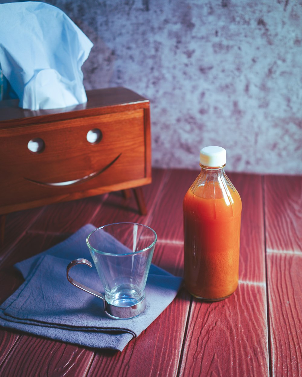 clear glass bottle beside clear drinking glass on brown wooden table