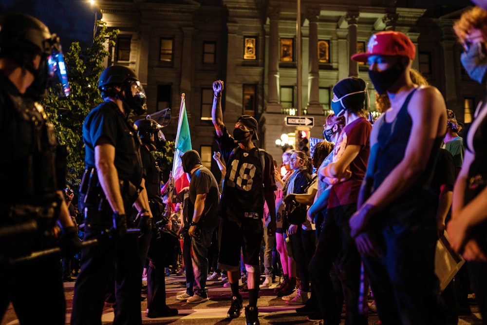 people in blue shirts and black pants standing on street during night time