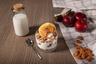 white and brown cake on white ceramic plate beside stainless steel spoon and clear glass jar