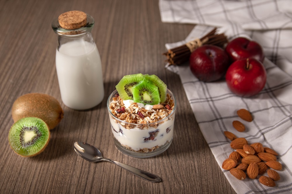 fresa y fruta verde en un cuenco de cerámica blanca junto a una cuchara de acero inoxidable