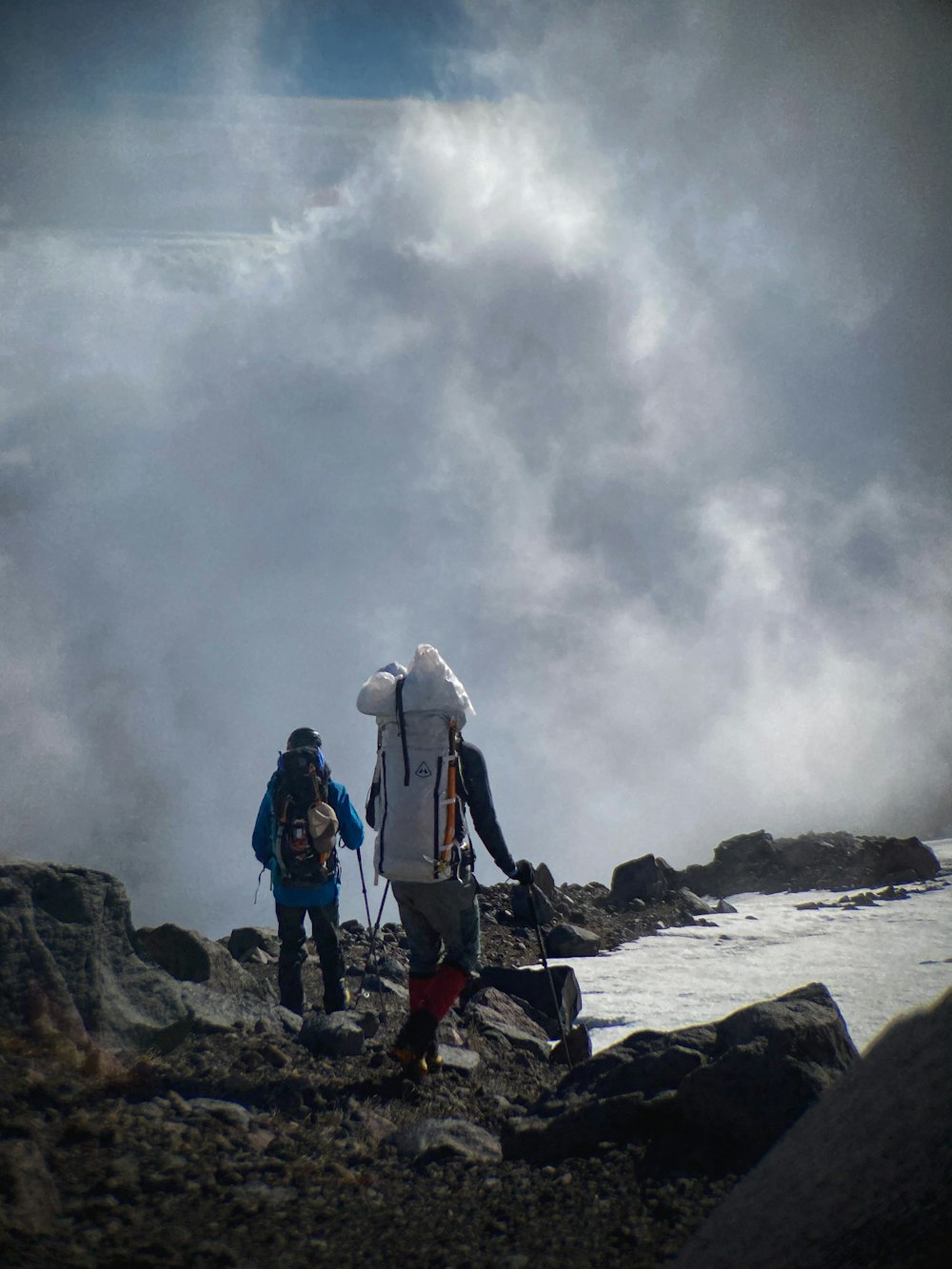 2 person standing on rock near body of water during daytime