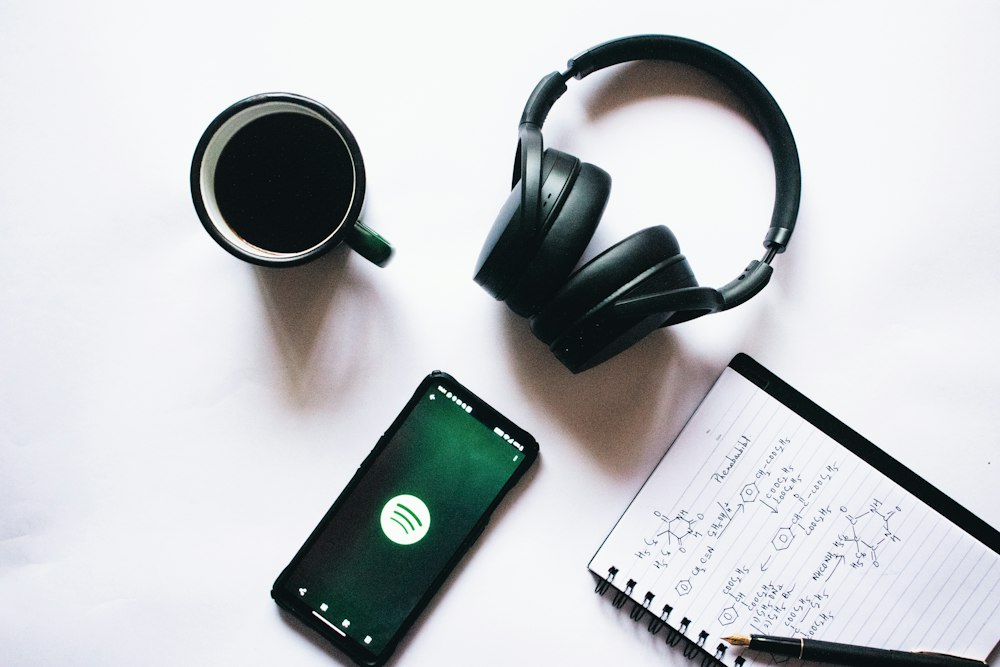 Notebook, pen and headphones on a dark desk