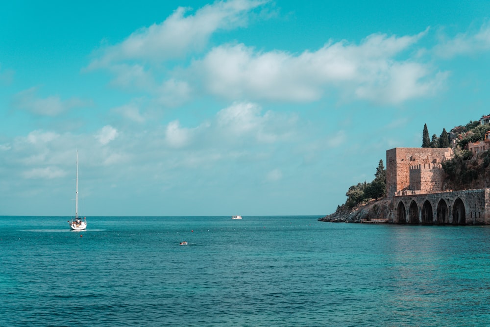 brown concrete building on island surrounded by water under blue sky during daytime