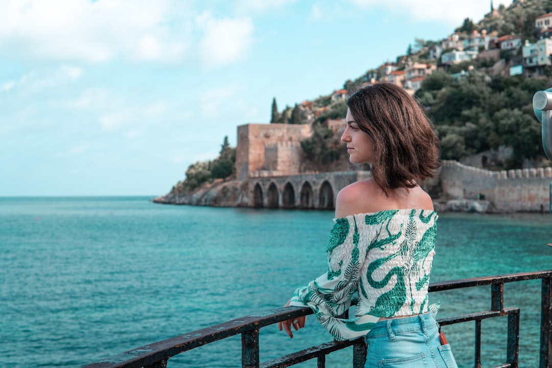 woman in green and white floral off shoulder shirt standing on bridge during daytime