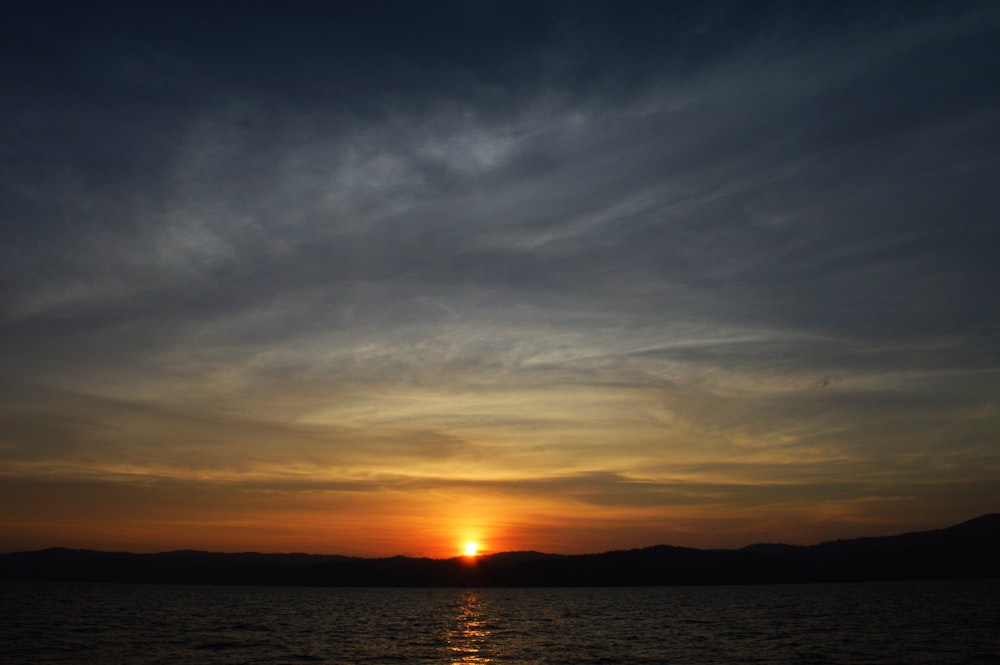 body of water under cloudy sky during sunset