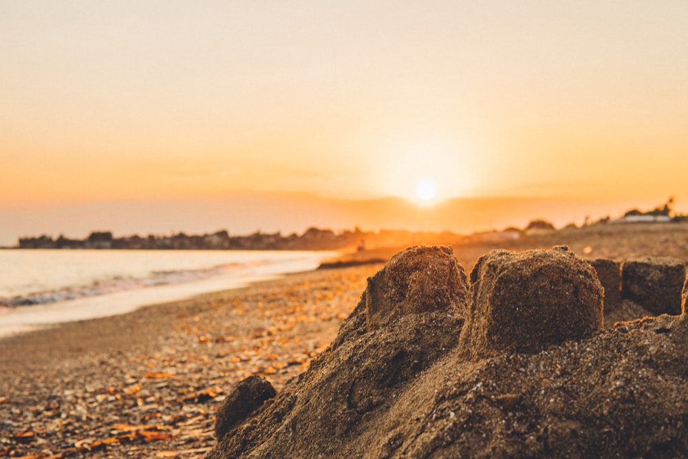 brown rock formation near body of water during sunset