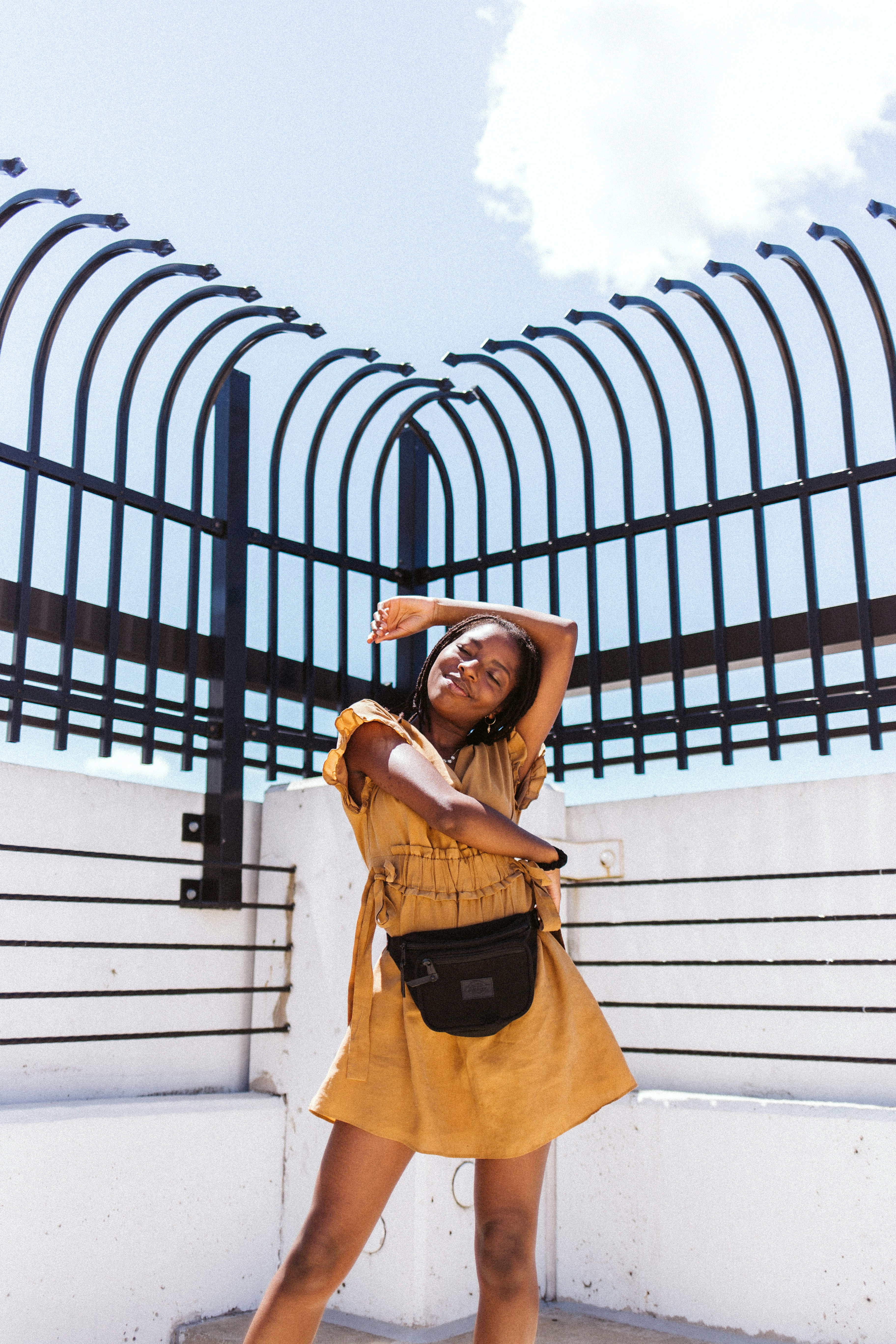 woman in brown long sleeve shirt and black skirt standing near white concrete building during daytime