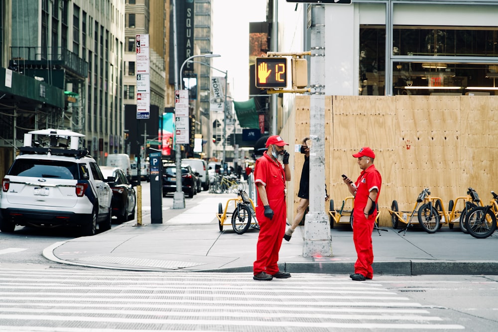 2 men in orange suit walking on sidewalk during daytime