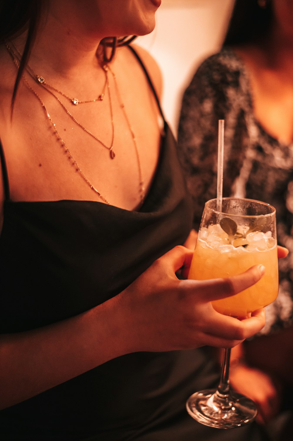 woman in black dress holding clear drinking glass with orange juice