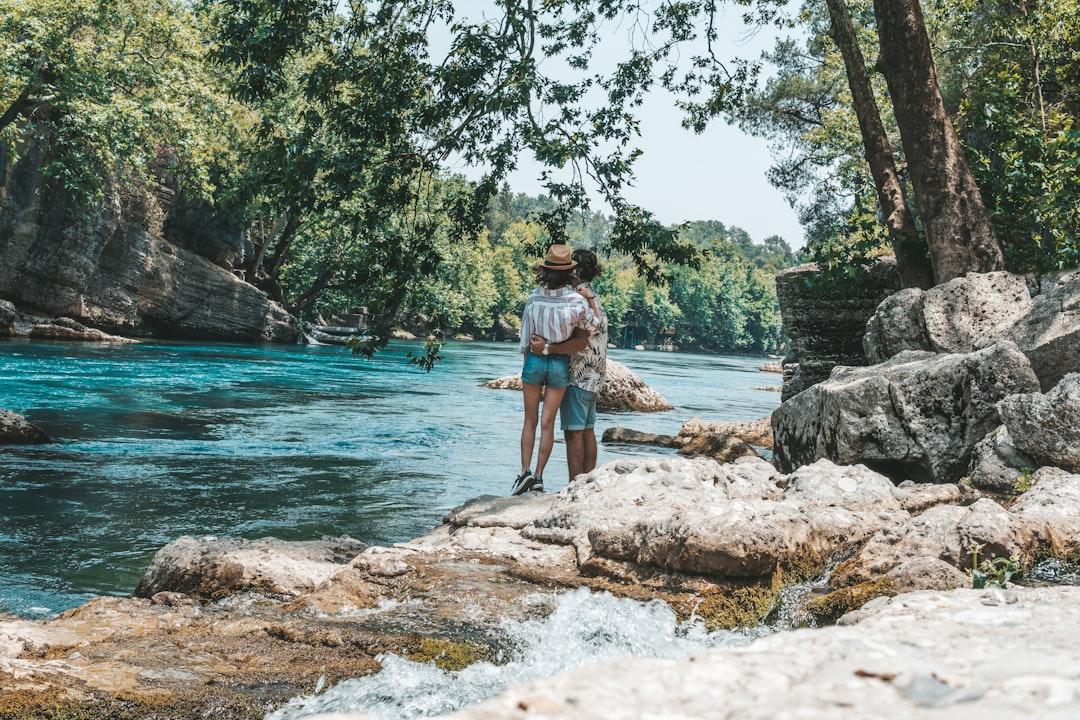 man in blue denim shorts standing on rock near body of water during daytime